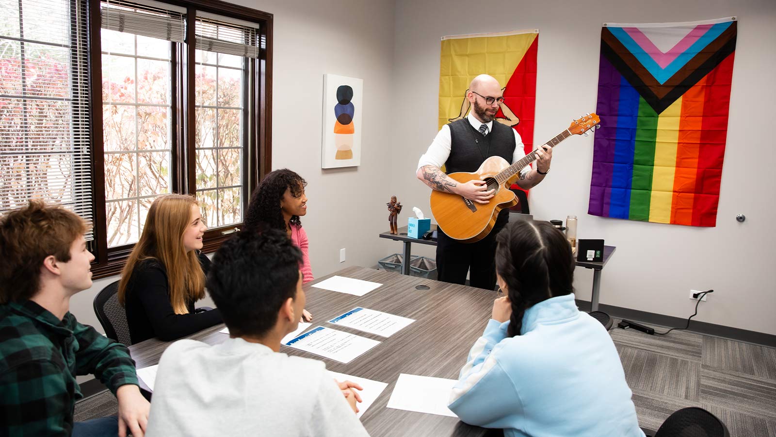 A group educational session where a teacher plays a guitar for students.