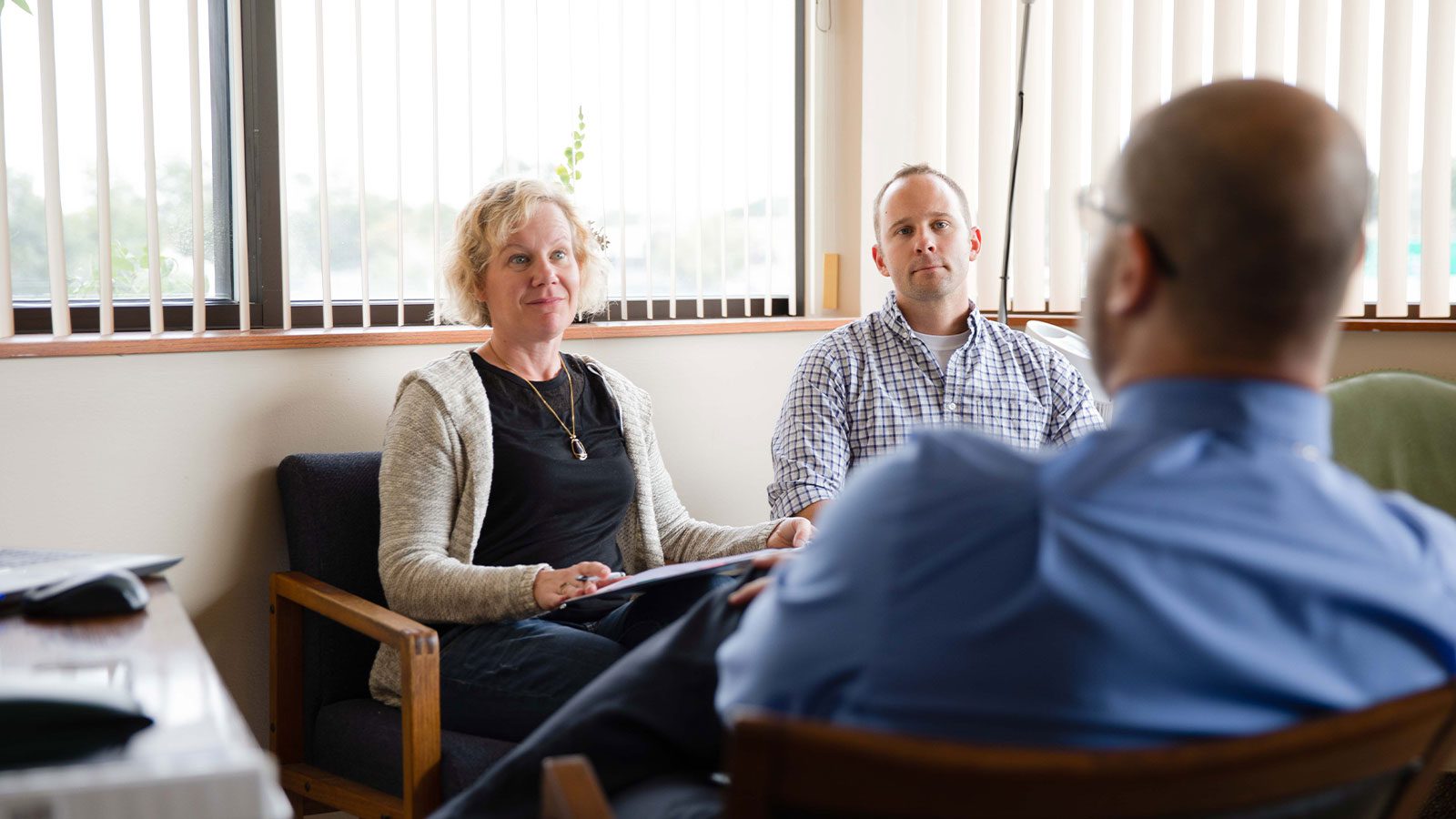 A focused group discussion involving professionals and parents in a bright room with large windows.