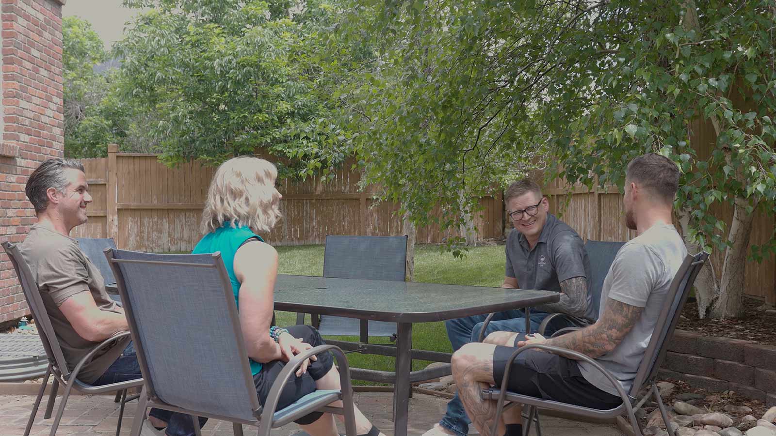 Four people enjoying a conversation at an outdoor patio.