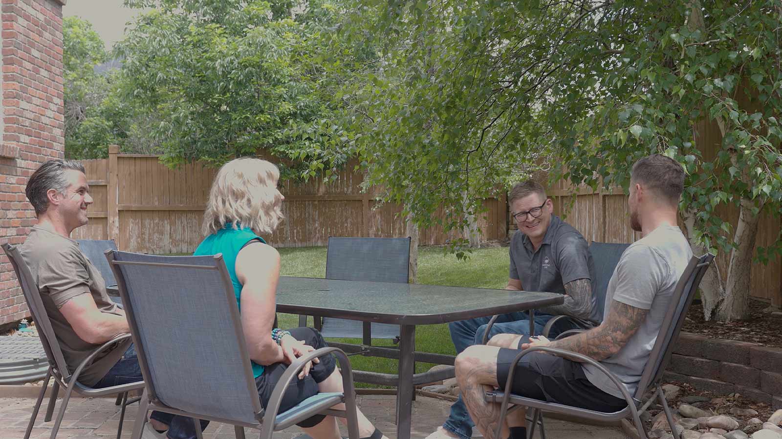 several people sitting around a table outside in a backyard