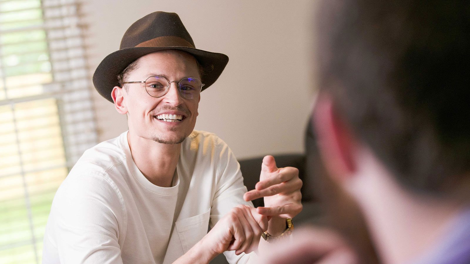 A man in a white shirt and hat smiling.