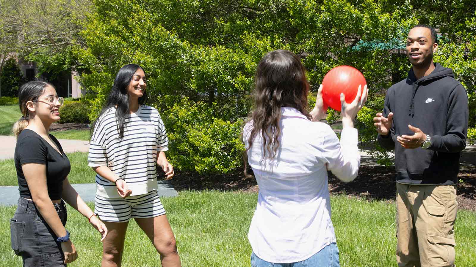 Four young adults having fun outside throwing around a ball.