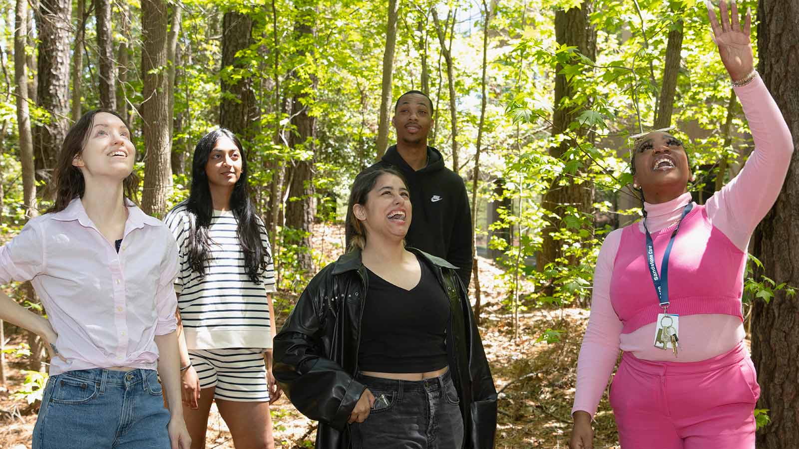 Four young adults and a professional going on a walk through the woods.
