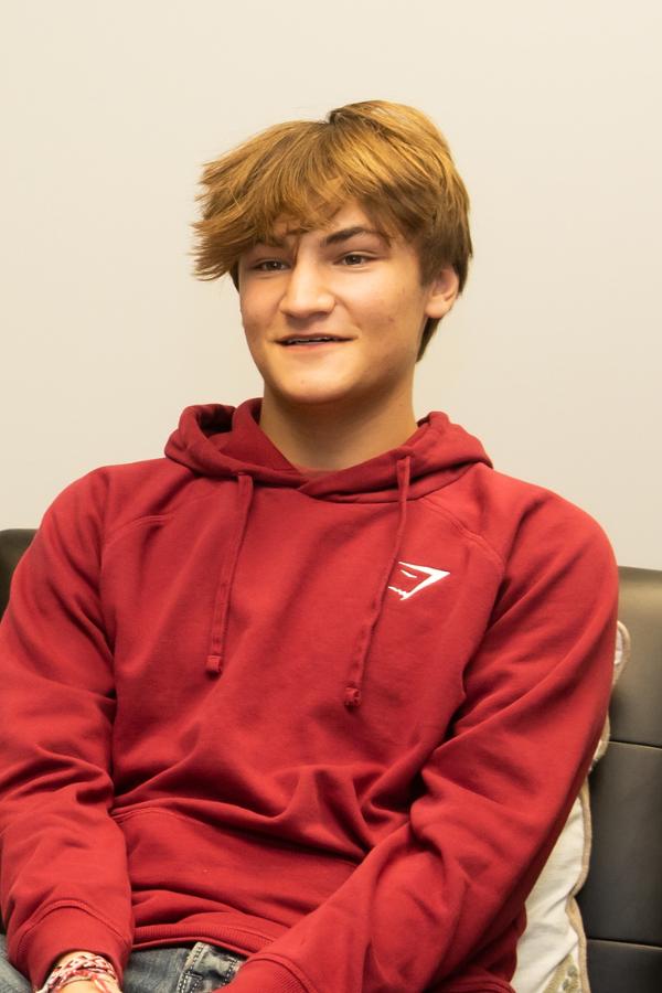 A teenage boy sitting on a leather couch.