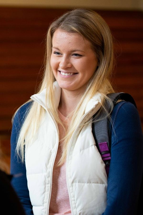 Young adult woman smiling with a backpack.