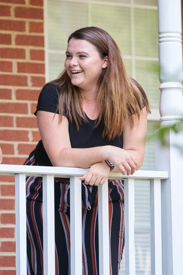 A teenage girl laughing on a balcony.