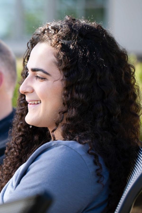 A young woman with dark curly hair smiling.