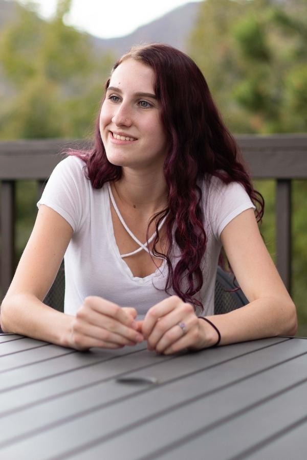 Teenage girl sitting outside with mountains in the background.