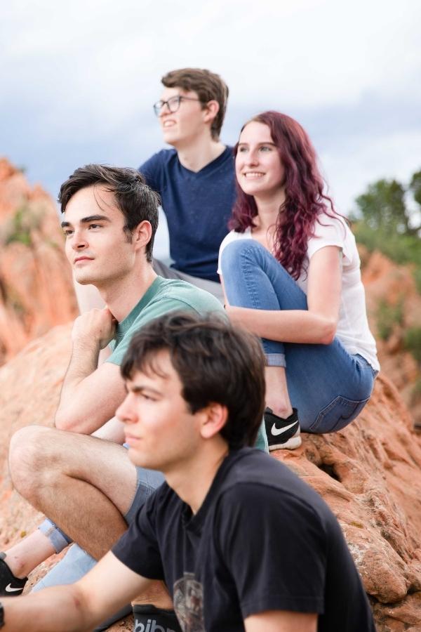 A group of teens sitting on red desert rocks.