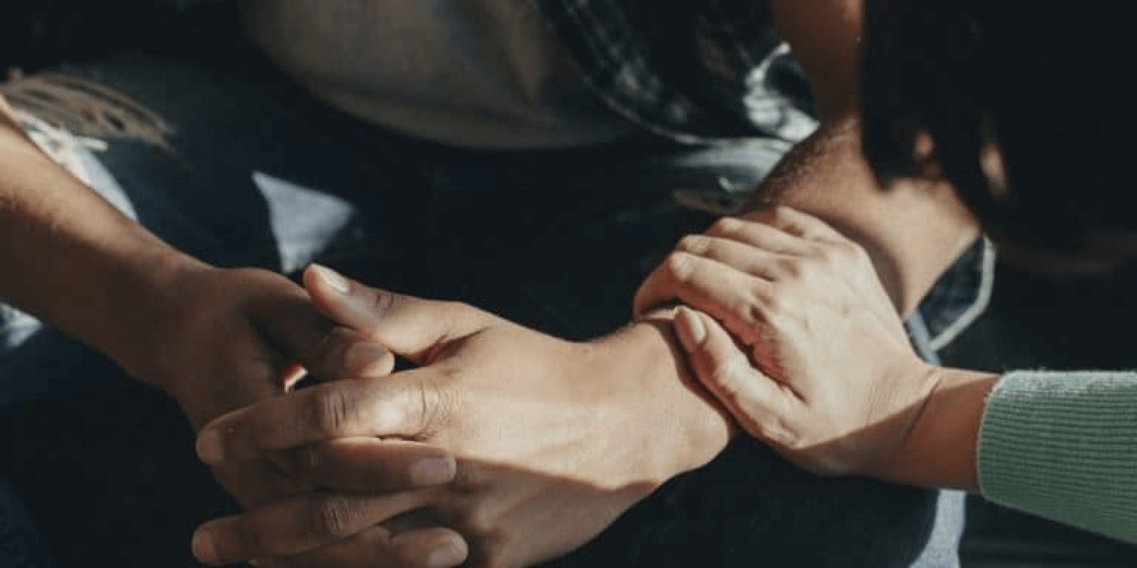 Someone holding hands together and the other warmly consoling them by putting hands on his arm