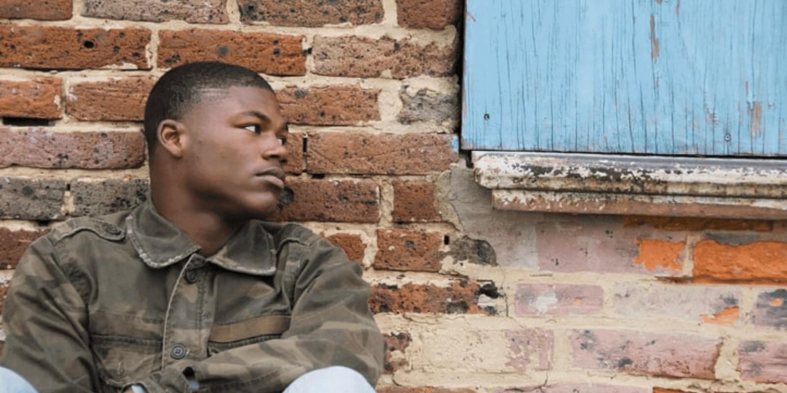 Teen looking away while leaning against a brick wall