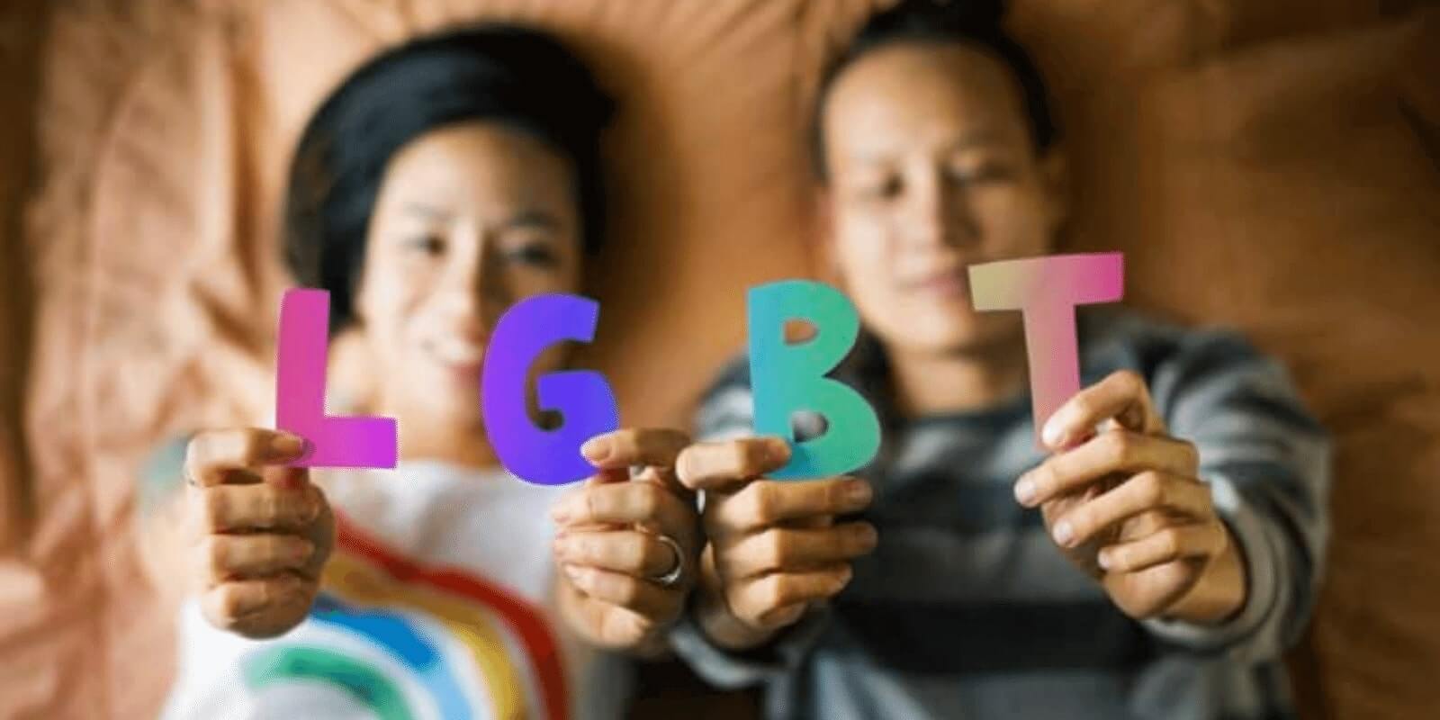 Two teens holding LGBT letters