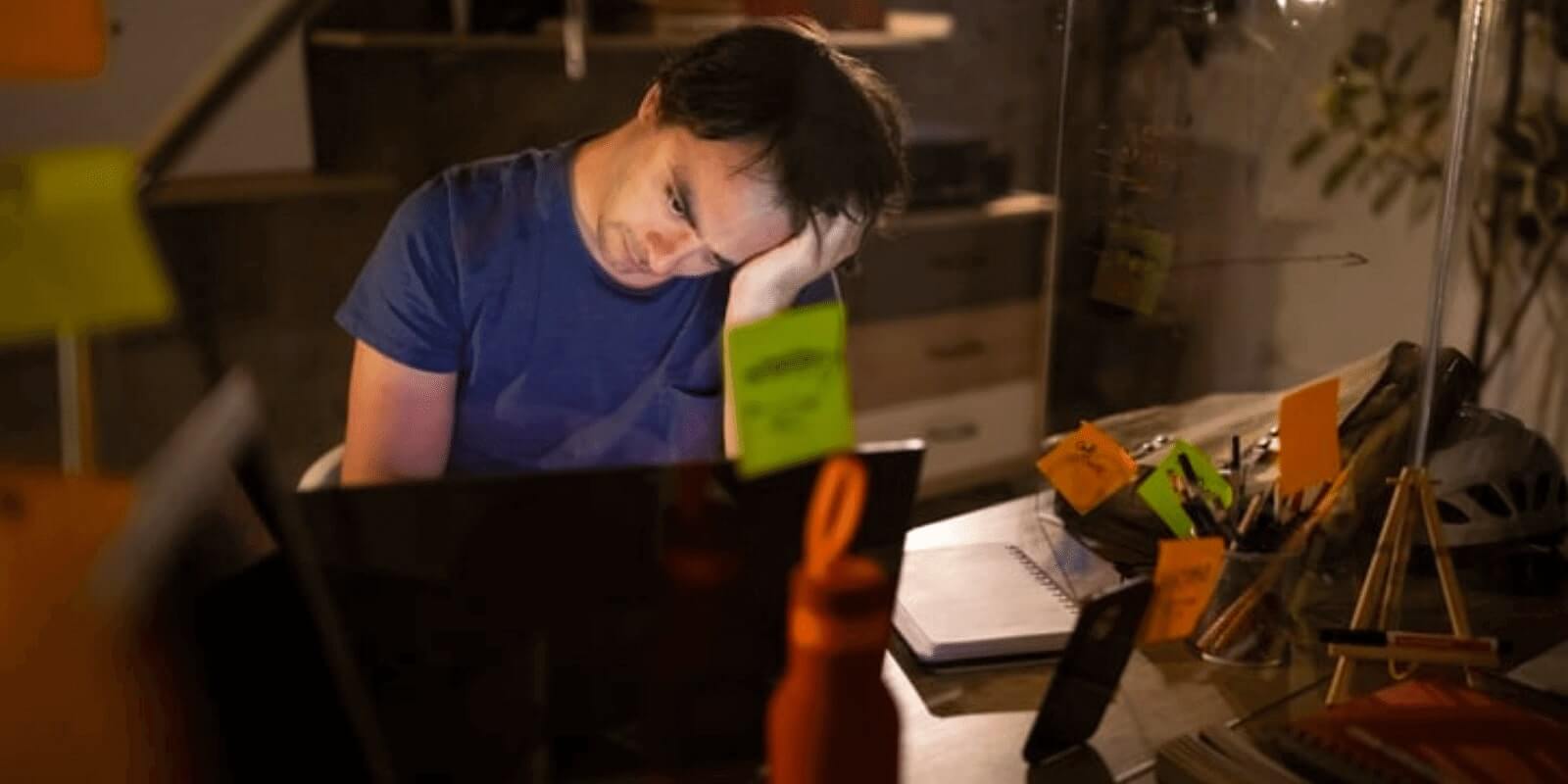 A young man looking depressed while looking at a monitor