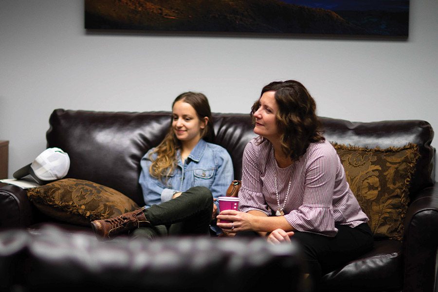 Mother and daughter comfortably seated on a leather sofa.