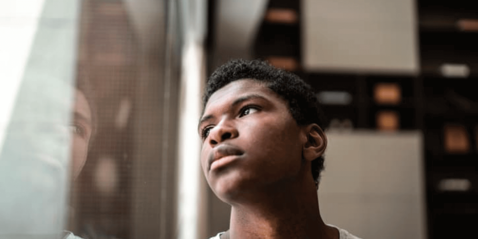 A young black boy looking through window