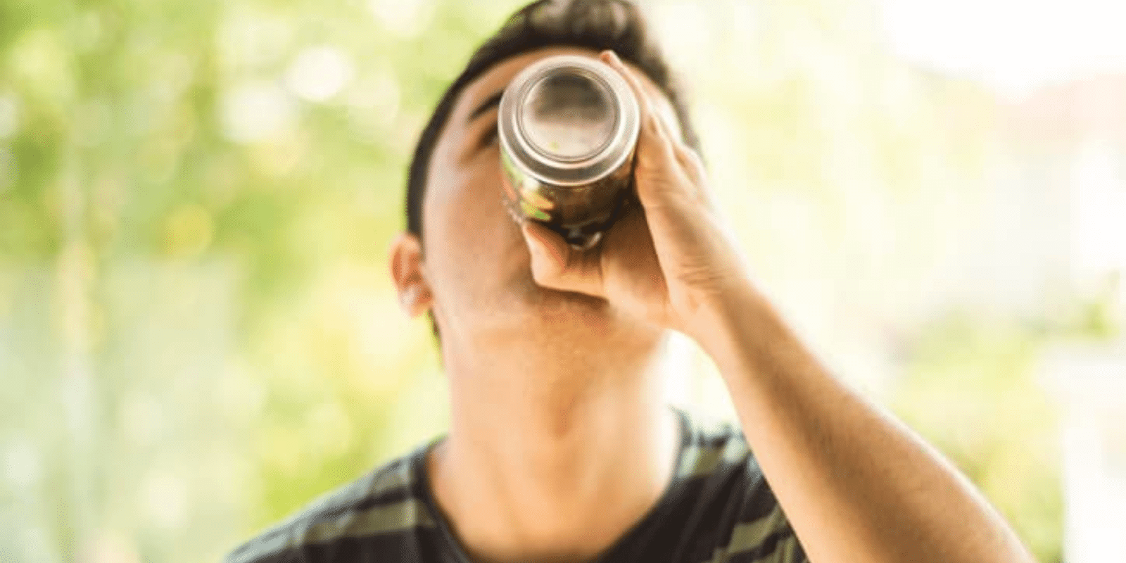 A teen boy drinking something from a can
