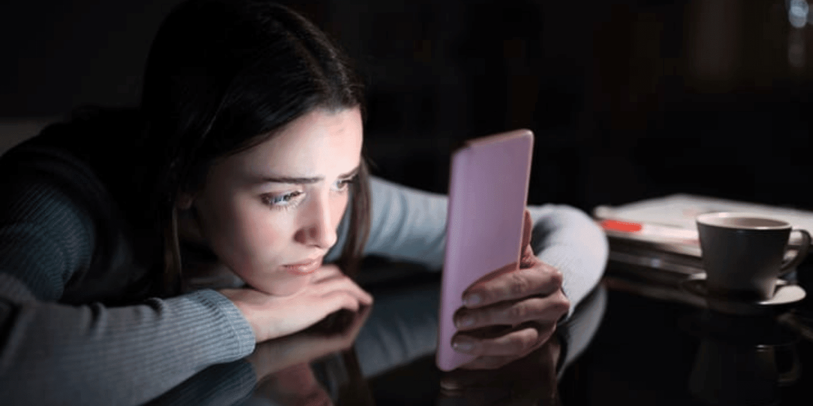 A teen girl looking at her smartphone in the dark