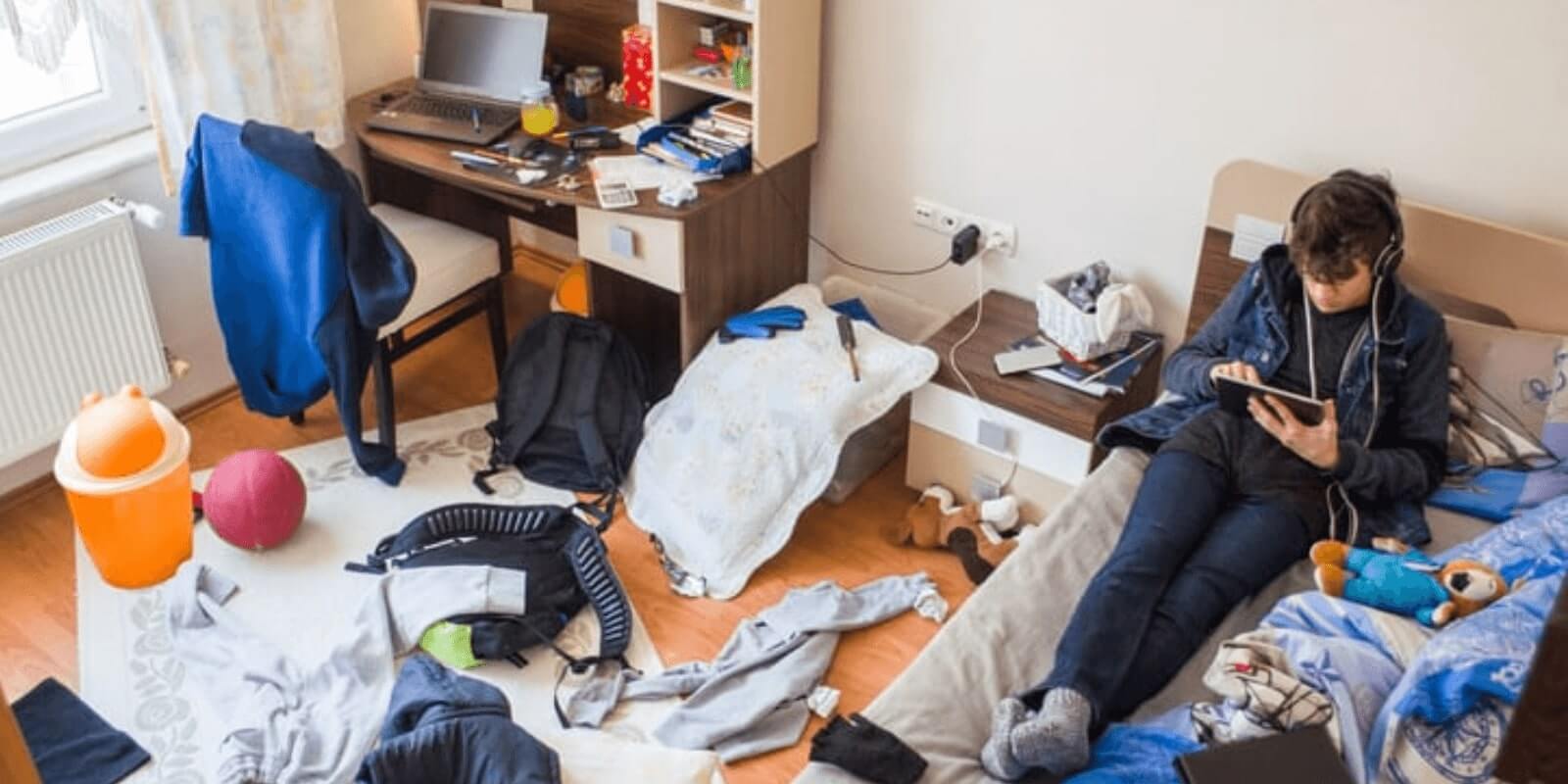 kid laying on bed on phone. clothes all over the floor