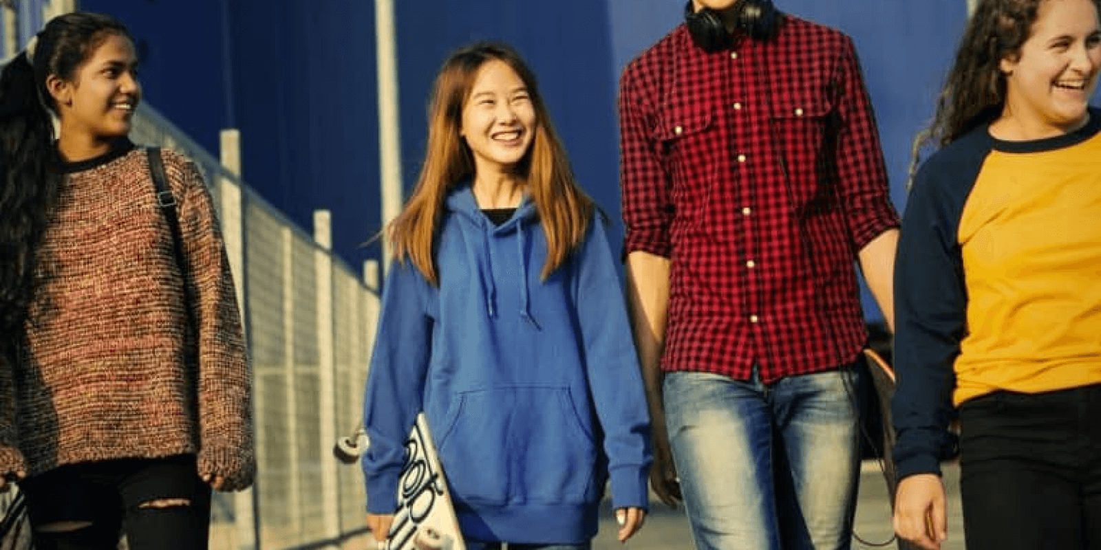 Group of young adults each wearing different color t-shirt, smiling and walking down the street