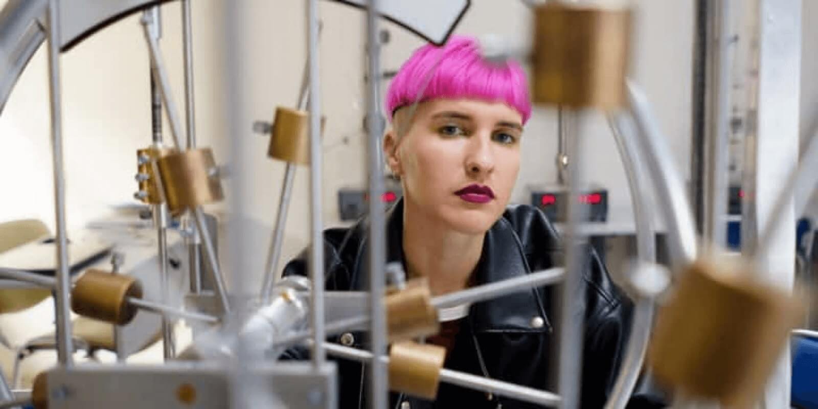 A pink hair teen wearing a black leather jacket in a science room