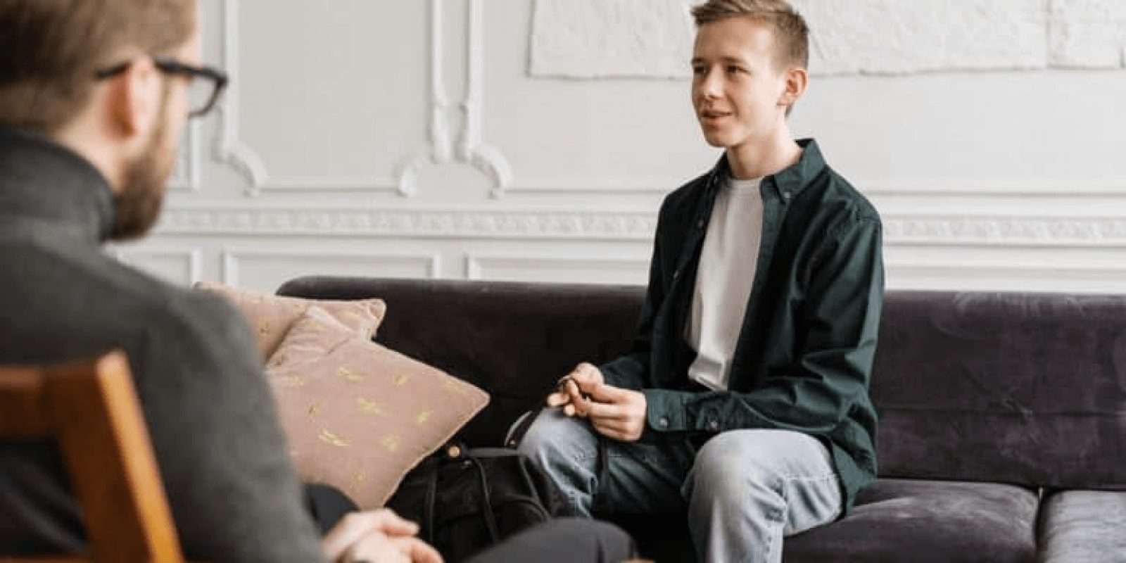 A teen boy participating in an individual therapy session with a male therapist