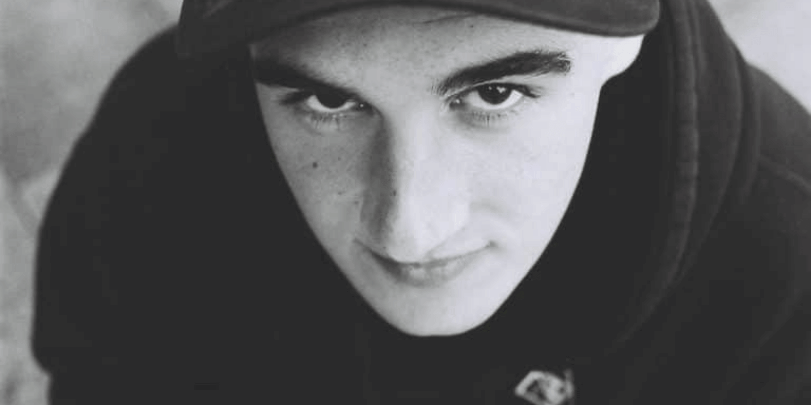 A teen boy wearing a hoodie looking up from below