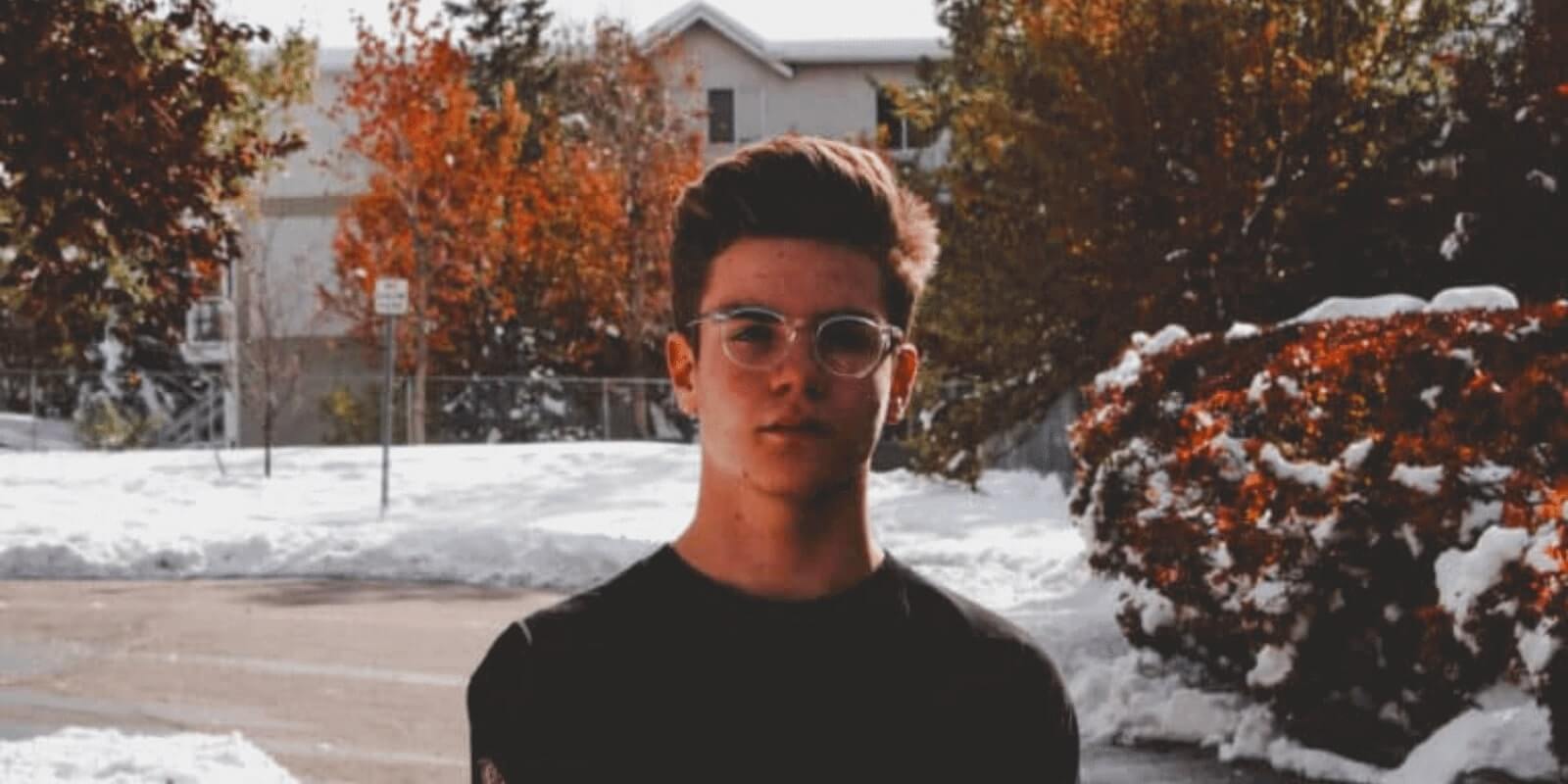 A teen boy standing on a road covered with snow