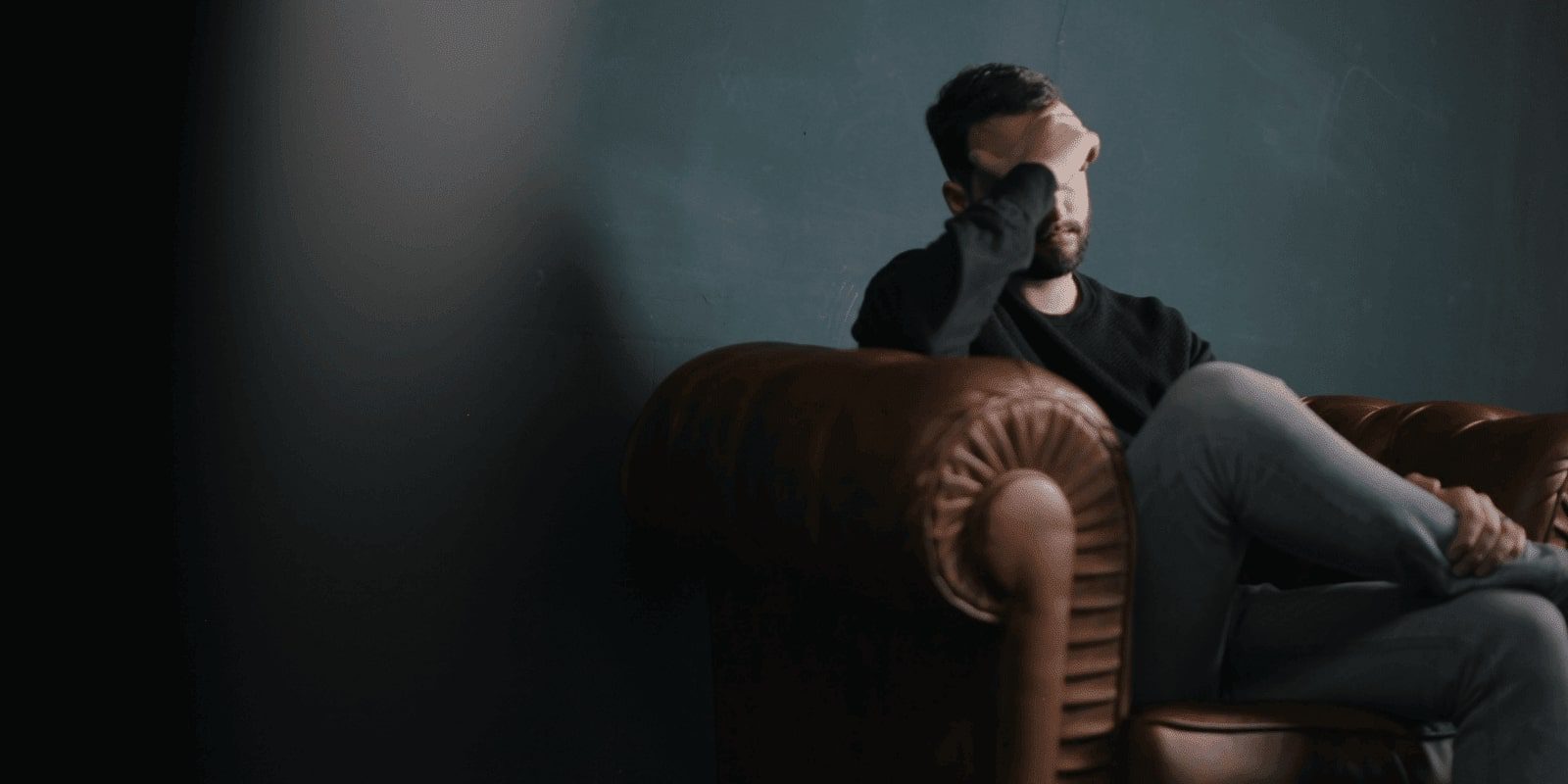 A male young adult sitting on the couch looking stressed