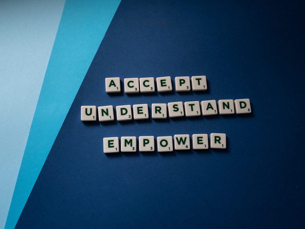 Alphabet tile spelling Accept, understand, empower on a blue background