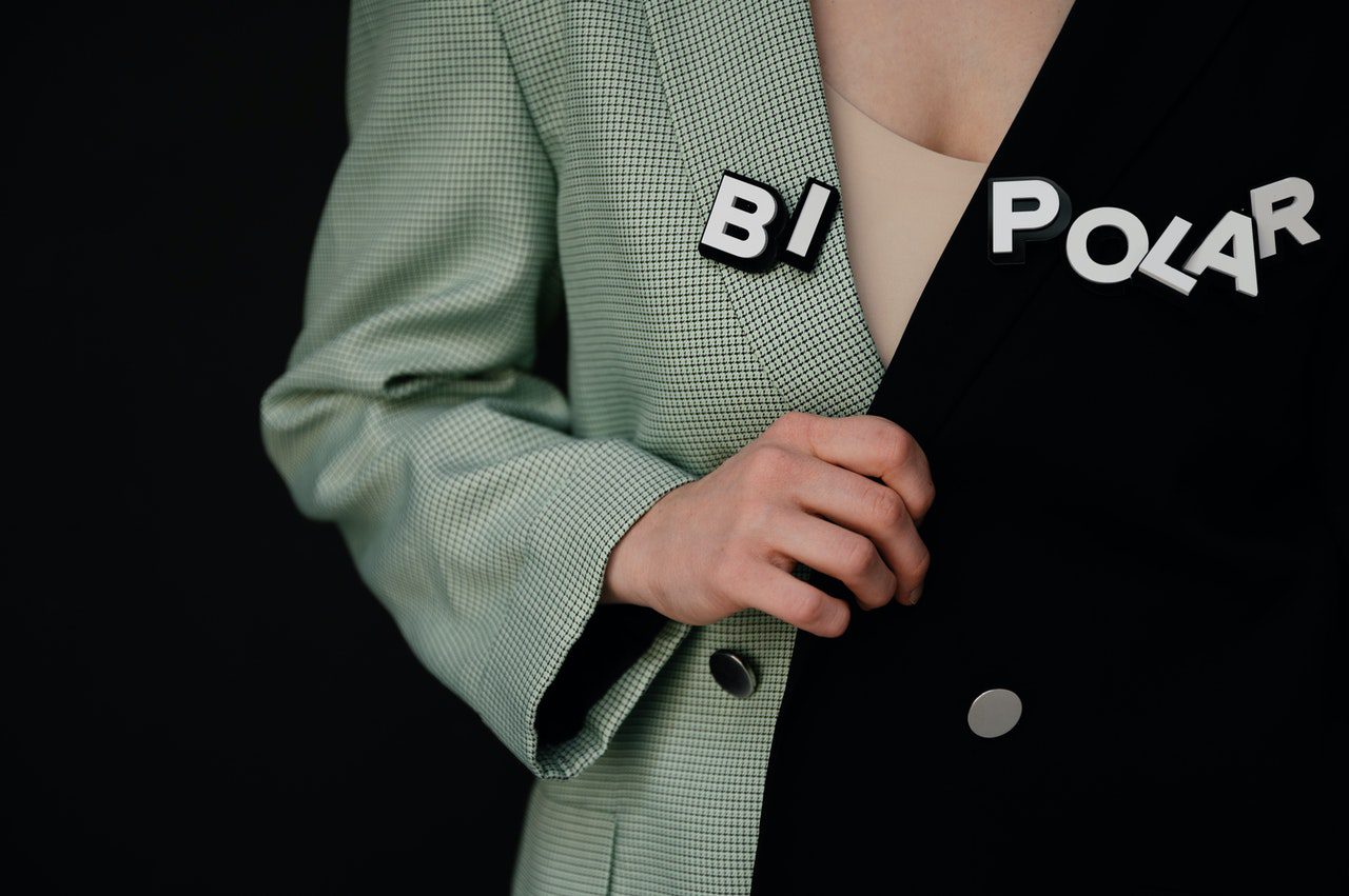 A woman wearing a two-sided jacket with a "BI" & "POLAR" badge on each side.