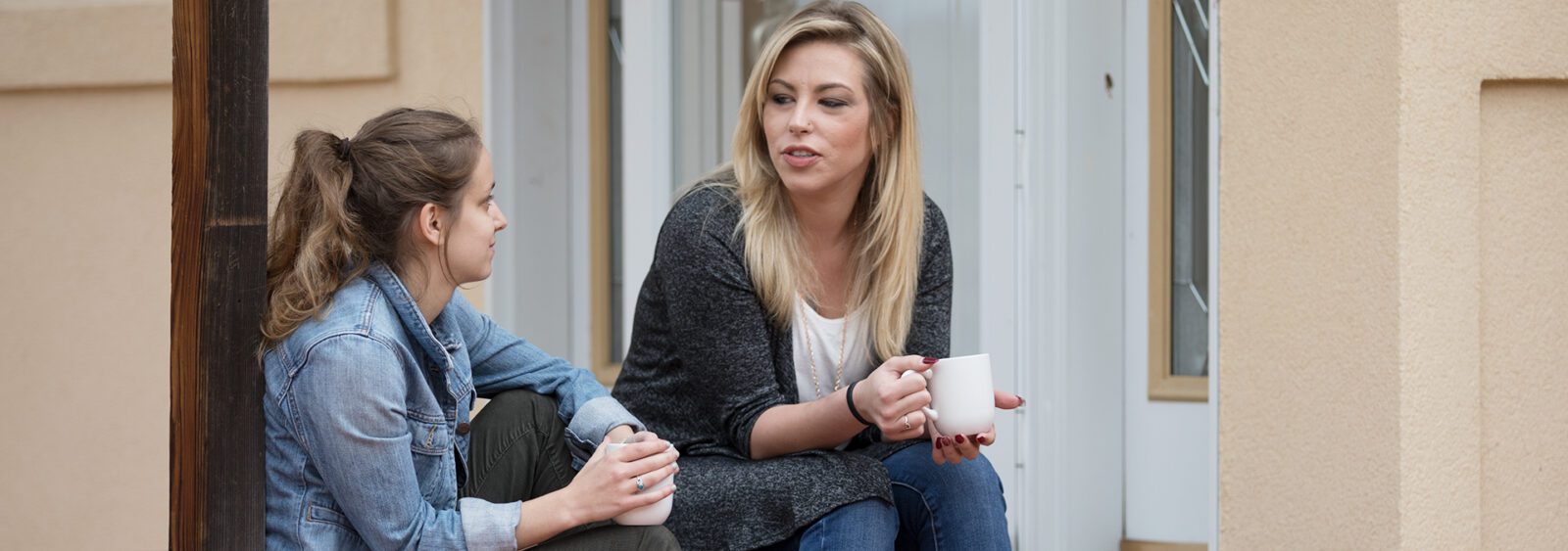 Two women sitting on a porch having a close conversation.