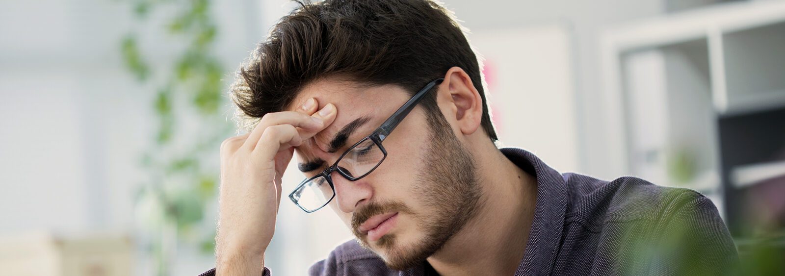 young adult man with his face in his hands.