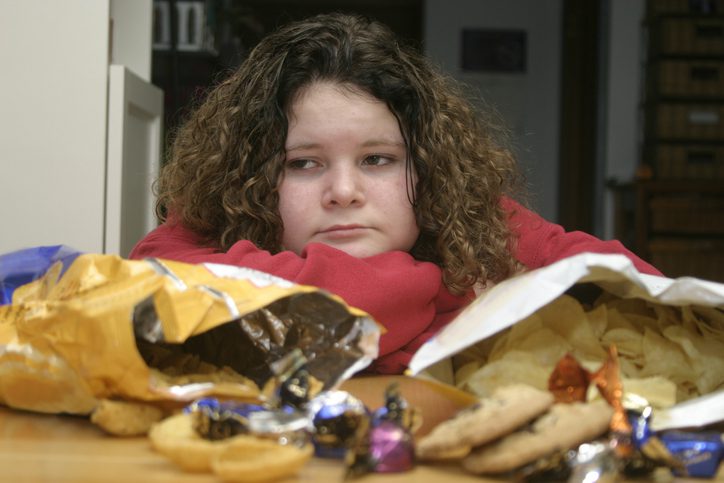 A teenage girl with her arms crossed on a table full of snacks