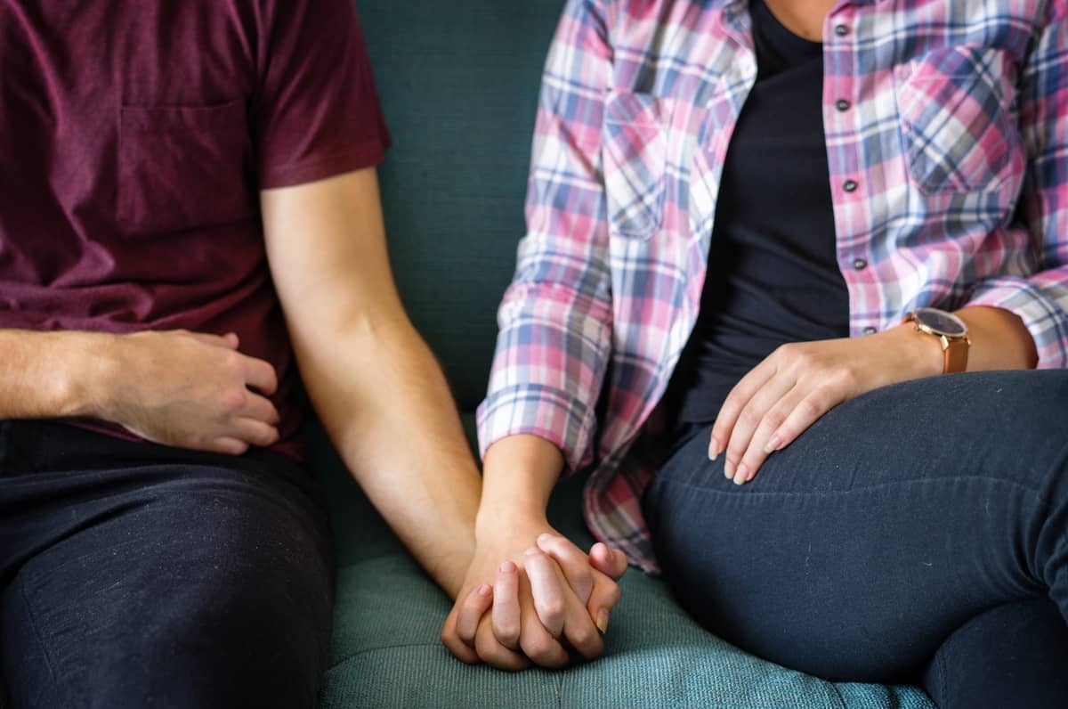 there are two people sitting on a couch holding hands