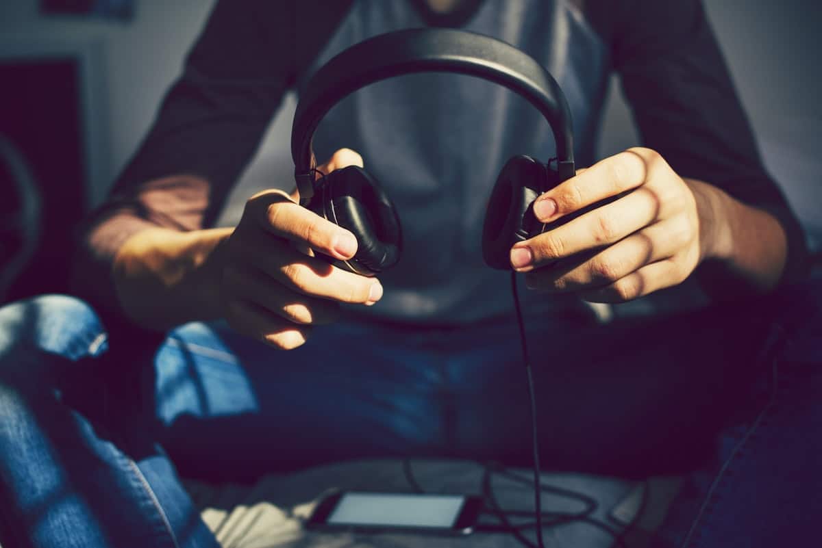 teen-holding-headphones-sitting-on-bed