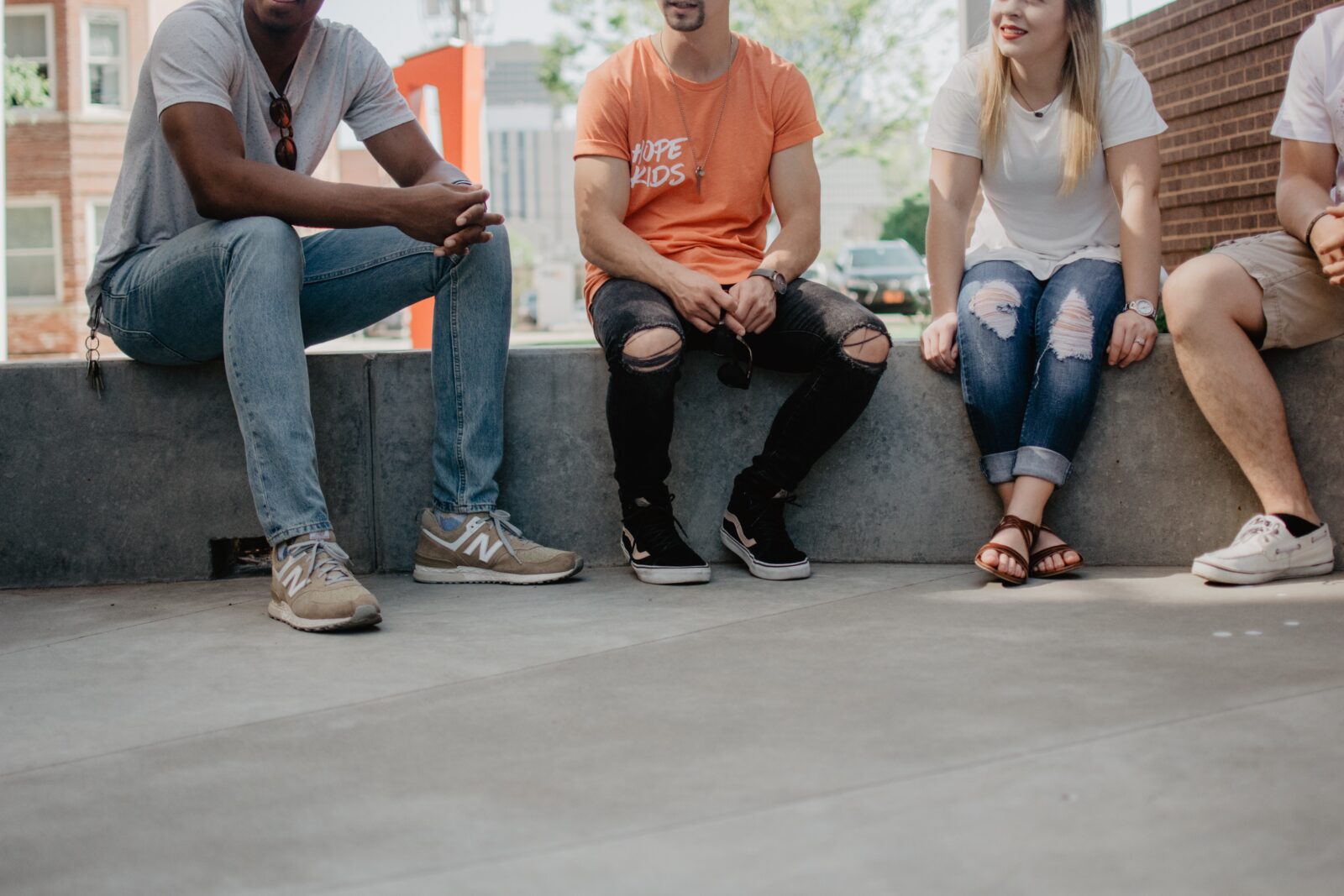 Four young adults sitting outside in a cityscape