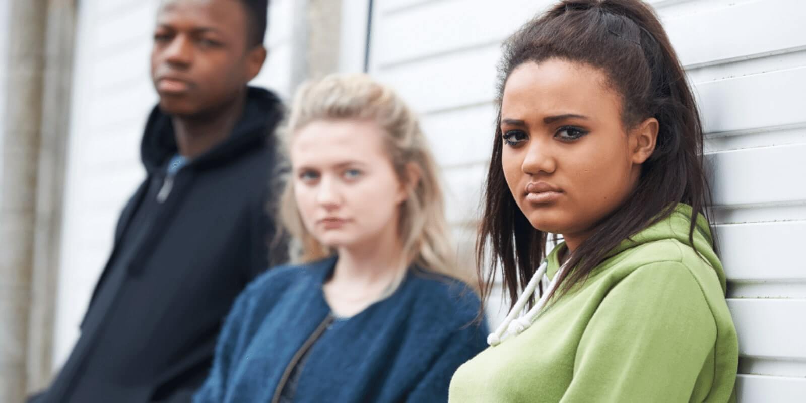 3 teenagers on standing against a white wall looking at the camera