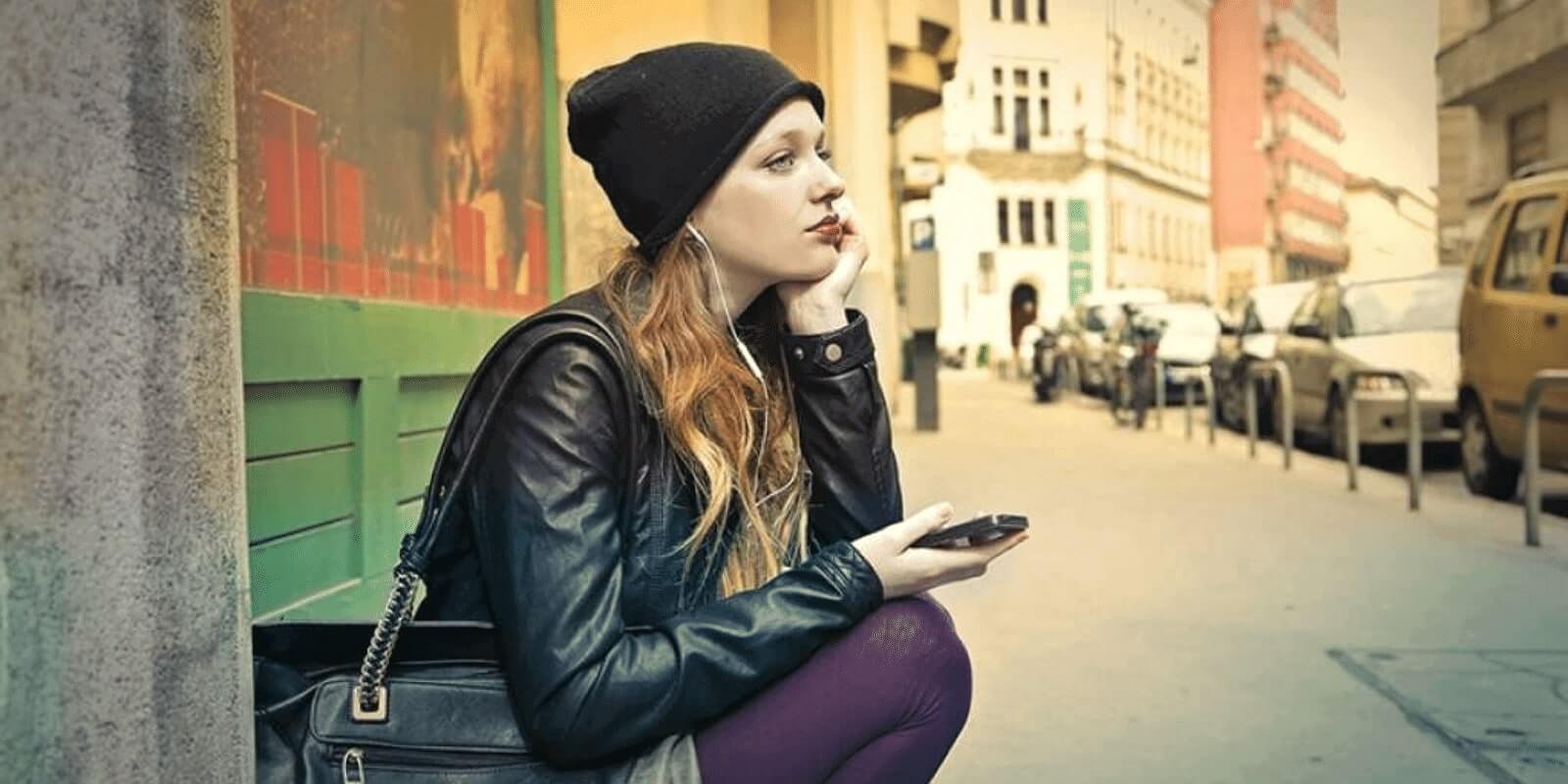 teen girl sitting on the street sadly