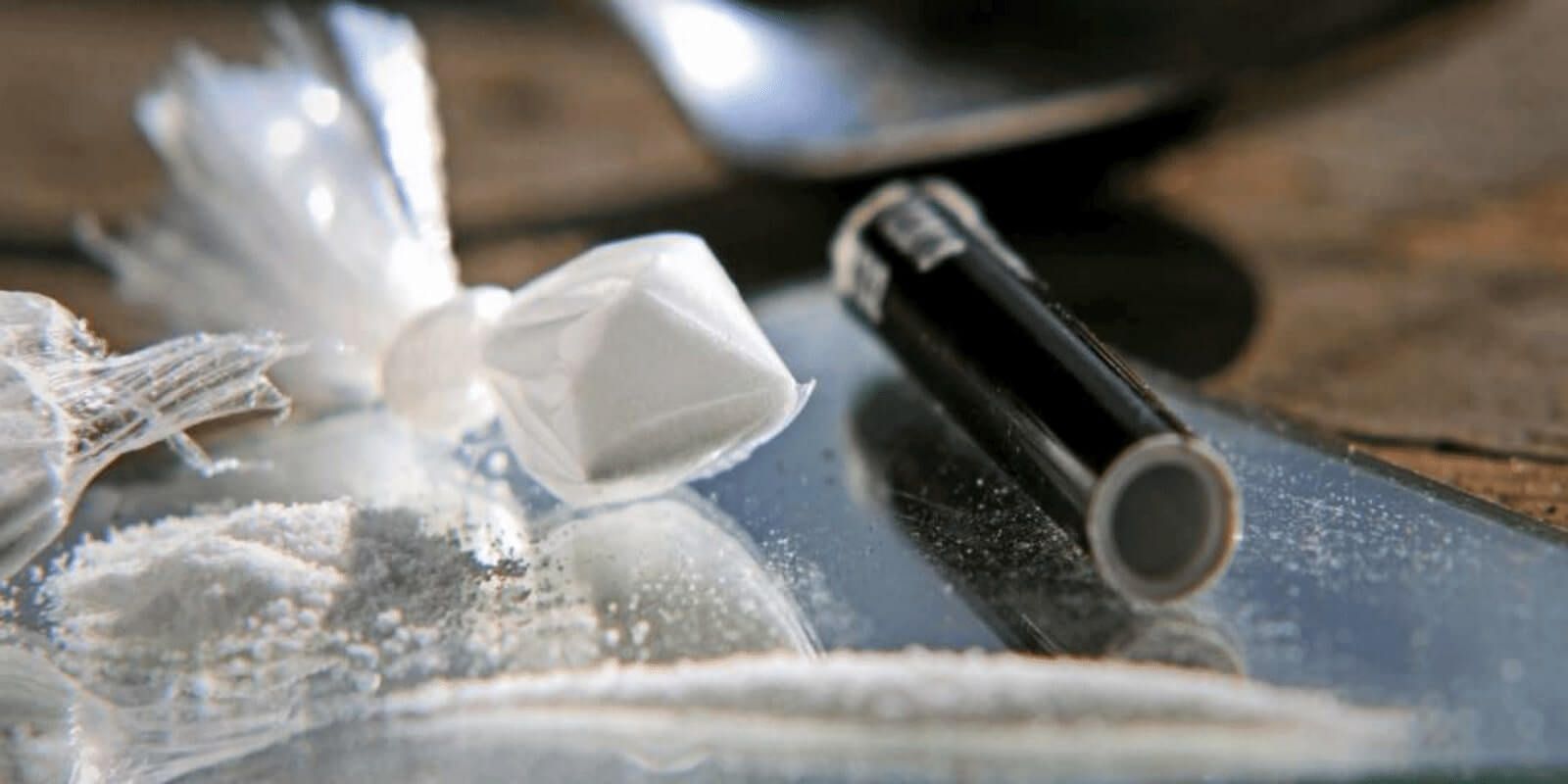 Meth powder on table with plastic bag and a small pipe