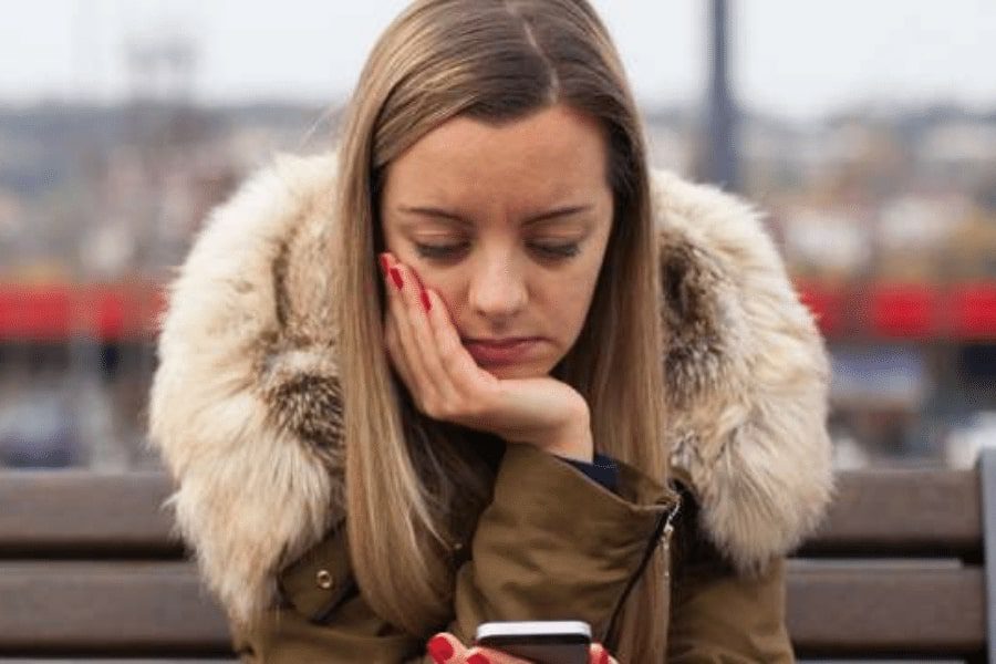 A girl looking at her phone in the winter street