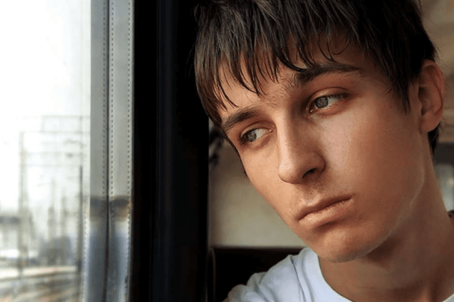 A sad looking teen looking over the train window