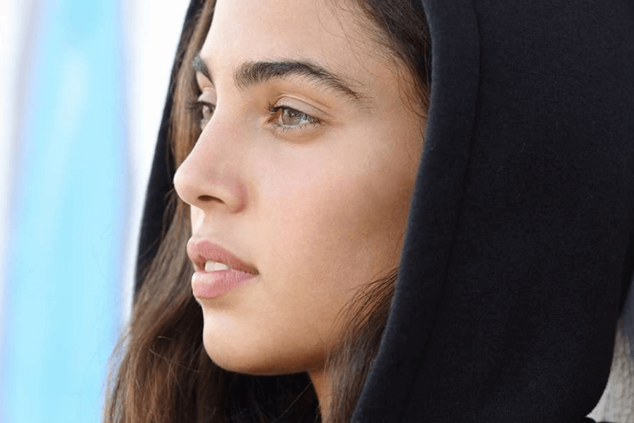 A female teen wearing a hood looking away