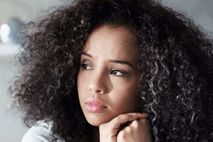 A black girl with makeup looking away on the left, seems concerned