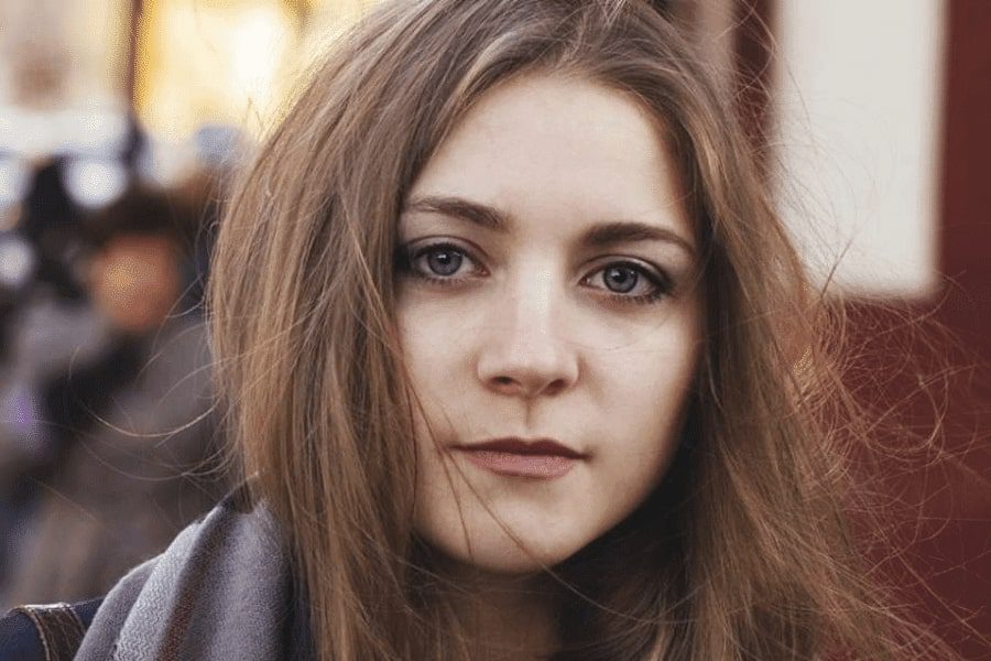 A teen girl staring at the camera mindlessly with a slight smile