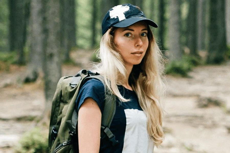 A young adult backpacking in the woods staring at the camera