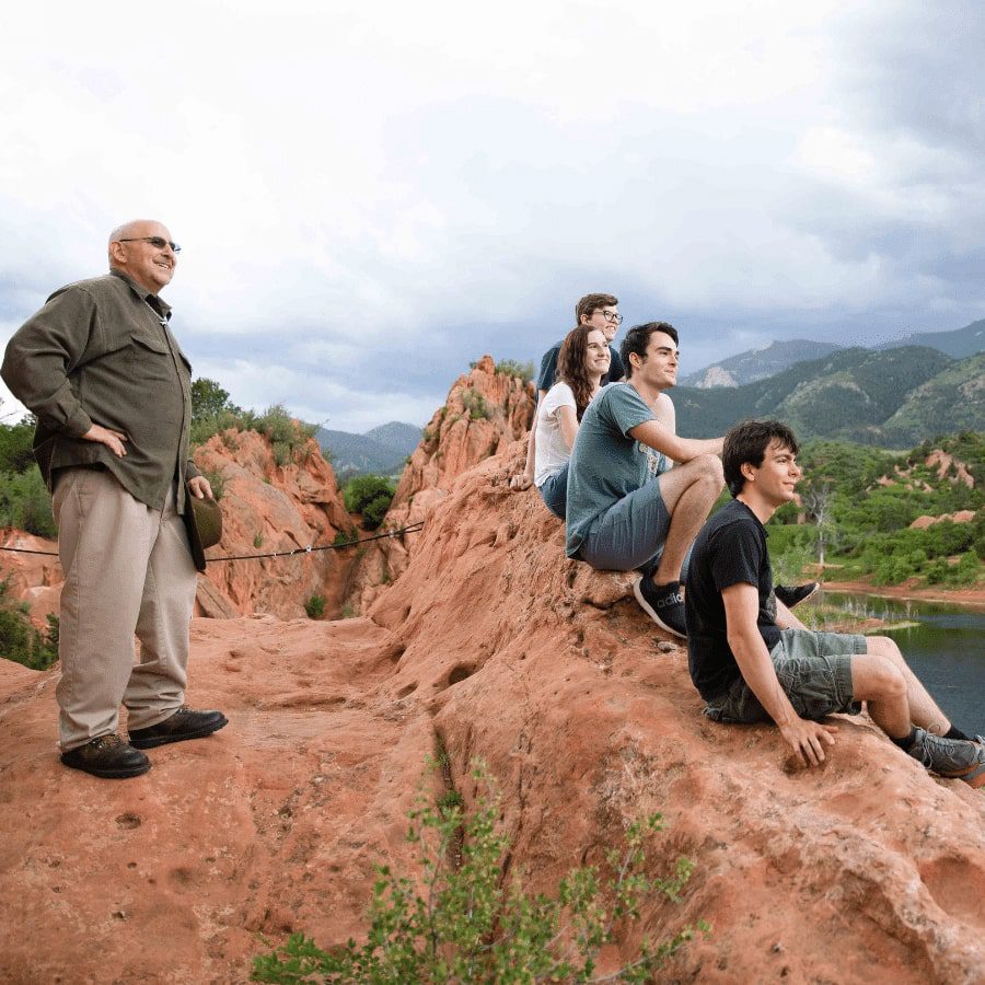 Teens and adult sitting on mountain