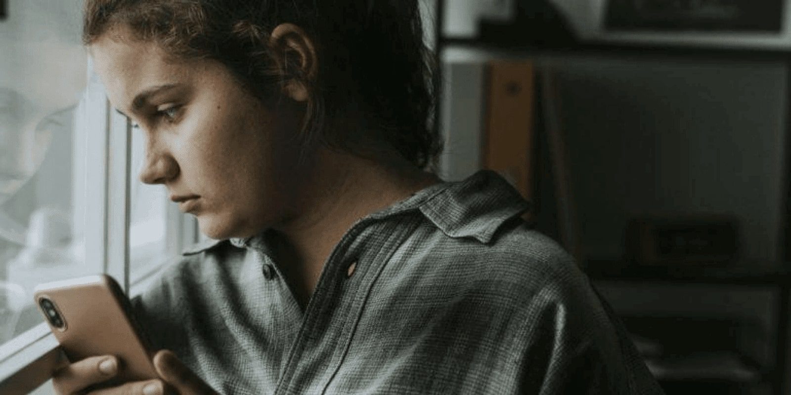 A teen girl holding a smart phone looking over the bus window