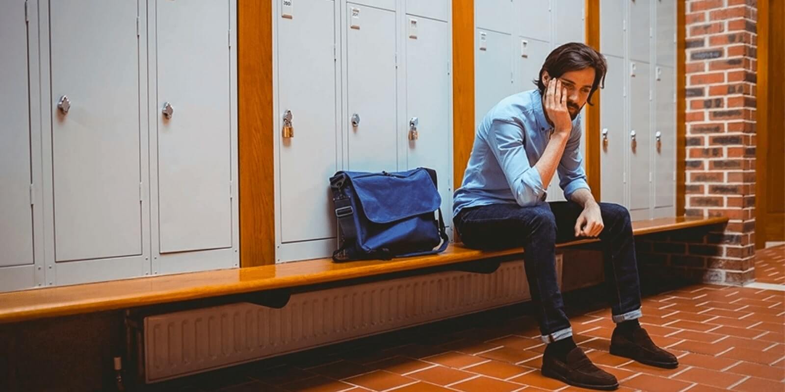 A college guy looking stressed in front of school lockers