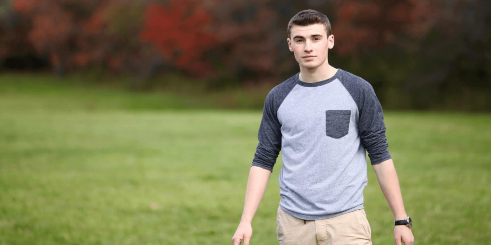 A young boy standing in a grass field