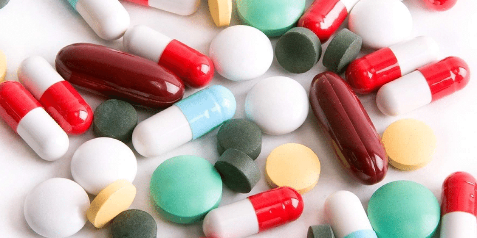 colorful pills and capsules scattered on a white background
